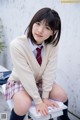 A young woman in a school uniform sitting on a bench.