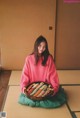 A woman sitting on the floor holding a bowl of sushi.