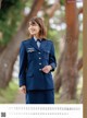 A woman in a blue uniform standing in front of a tree.