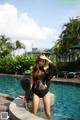 A woman in a black bathing suit standing in a pool.