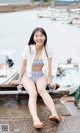 A woman in a blue and white bikini sitting on a dock.