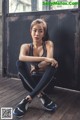 A woman sitting on a wooden floor in a gym.