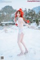 A woman in a white bodysuit and a red hat in the snow.