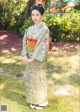 A woman in a kimono standing in the grass.