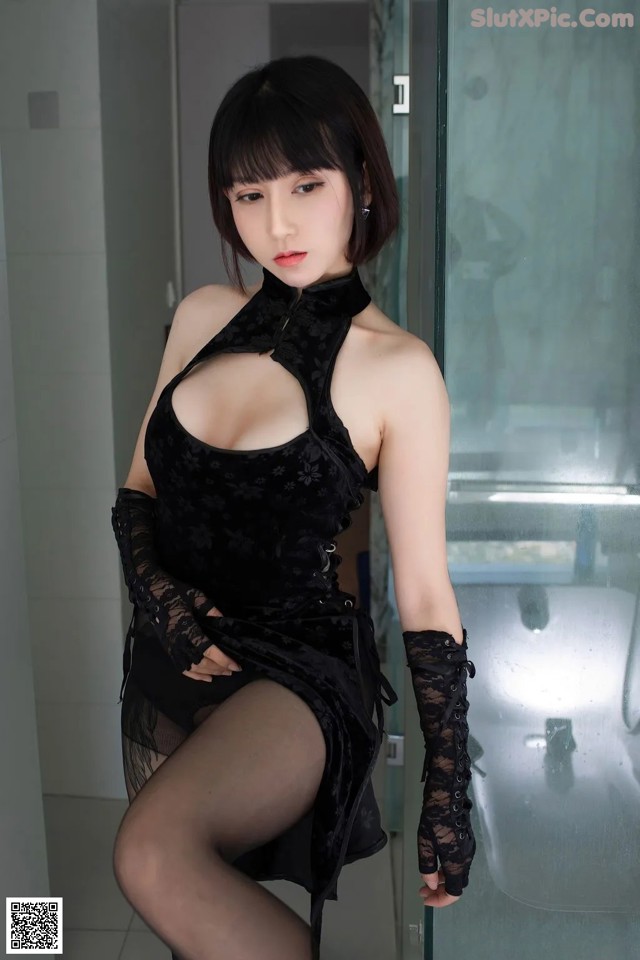 A woman in a black dress and gloves posing for a picture.