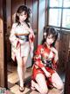 A couple of women in kimonos sitting on the floor.