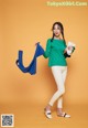 A woman in a green top and white pants holding a blue scarf.