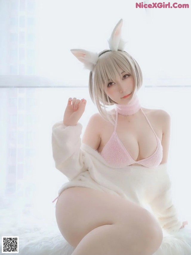 A woman in a bunny costume sitting on a bed.