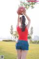 A woman in shorts and a red shirt holding a basketball.